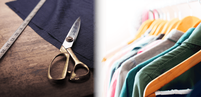 Tailor's scissors, tape and material on a table, blended with a rail of clothes on hangers