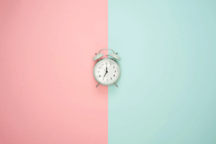 Alarm clock on pink and green background