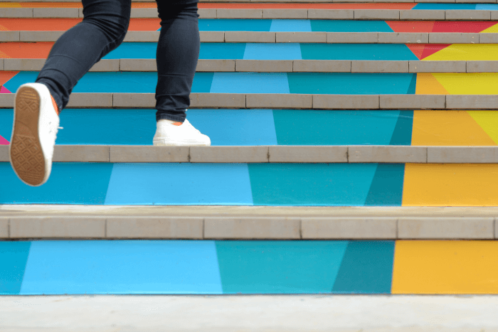 Legs in jeans walking up colourful steps
