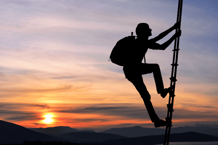Man in silhouette climbing rope ladder