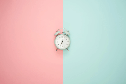 Alarm clock on pink and green background